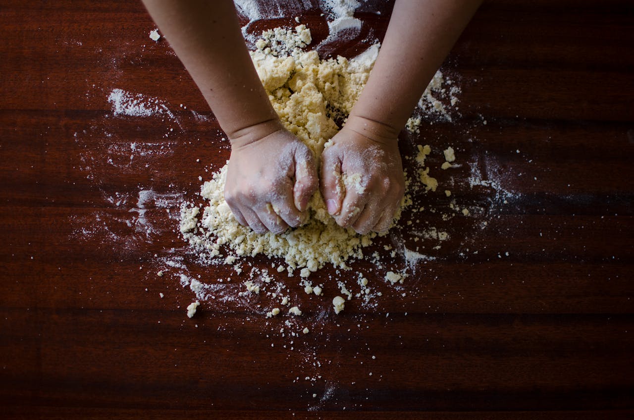 services-03 Close-up of hands kneading dough for baking on a wooden table, ideal for cooking themes.