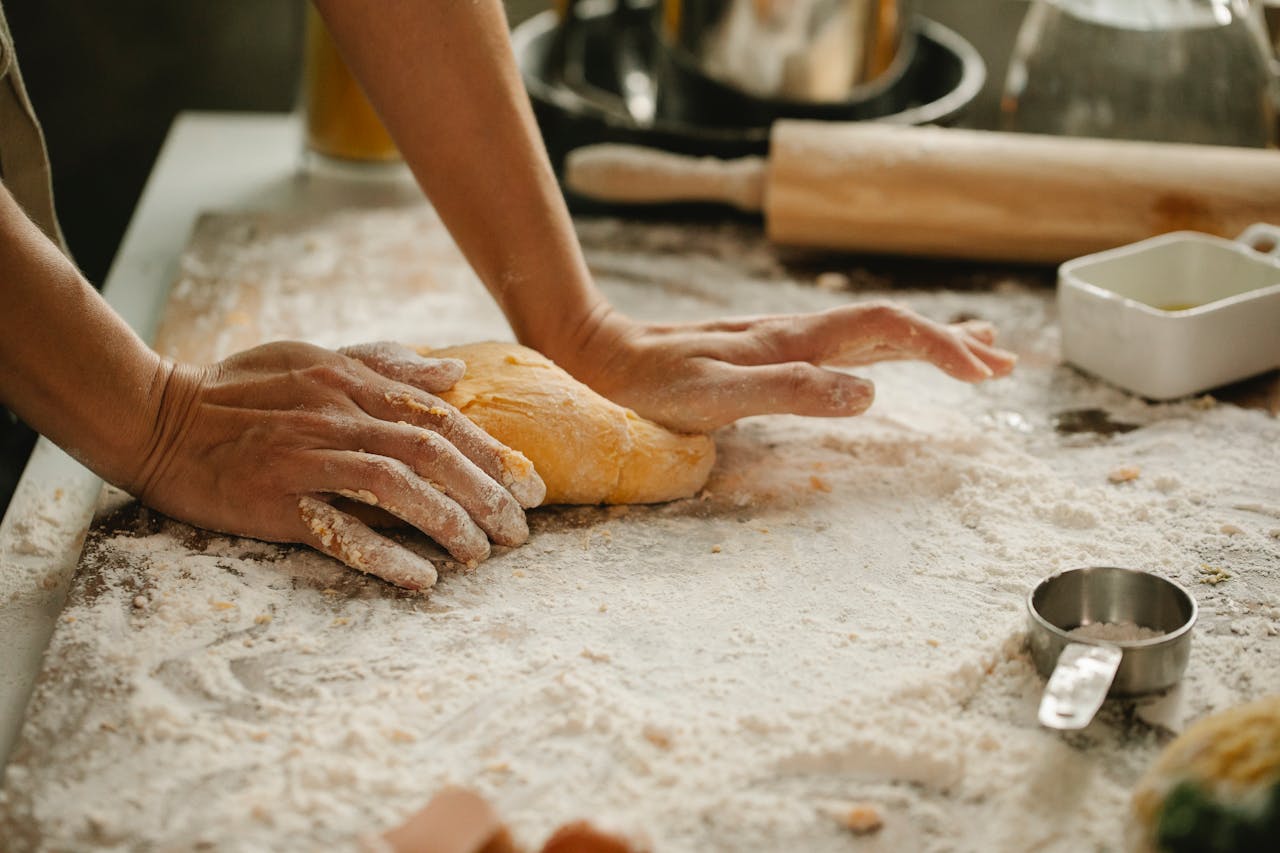 home-hero A person kneads fresh dough in a kitchen, showcasing the baking process.